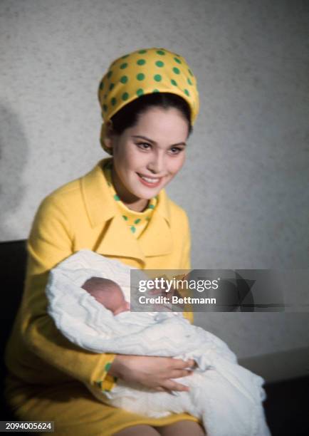 Ratna Sari Dewi Sukarno, wife of former Indonesian President Sukarno, holds her infant daughter, Kartika Sari, prior to leaving Keio University...