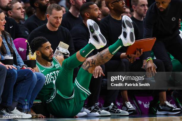 Jayson Tatum of the Boston Celtics falls into court side seats as a drink spills against the Washington Wizards during the first half at Capital One...