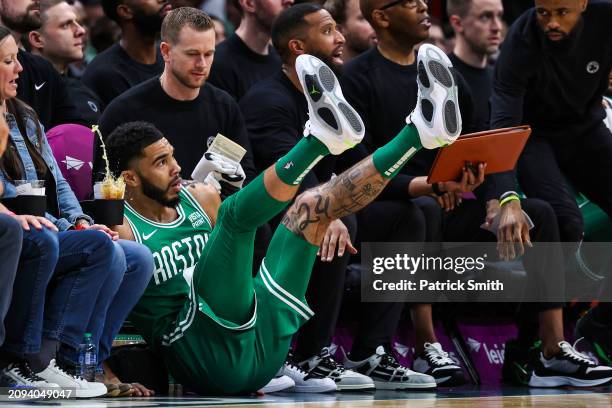 Jayson Tatum of the Boston Celtics falls into court side seats as a drink spills against the Washington Wizards during the first half at Capital One...