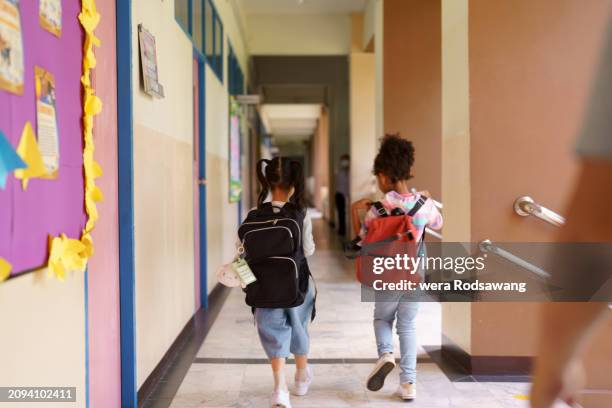back view of elementary children carrying school bag walking to classroom - cartable photos et images de collection