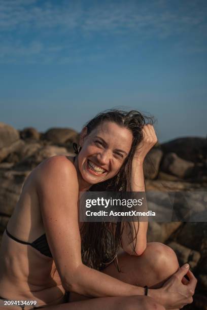 young woman relaxes on rocky shoreline - hand in hair stock pictures, royalty-free photos & images