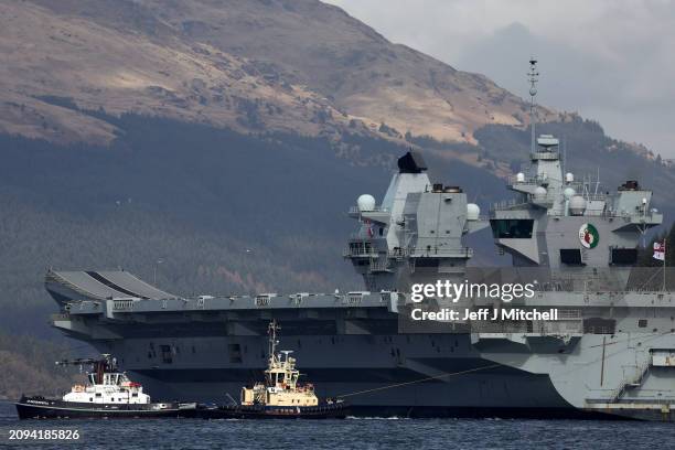 Queen Elizabeth air craft carrier is pulled by tugs on Loch Long on March 18, 2024 in Glenmallan, Scotland. HMS Queen Elizabeth was in Glenmallan in...