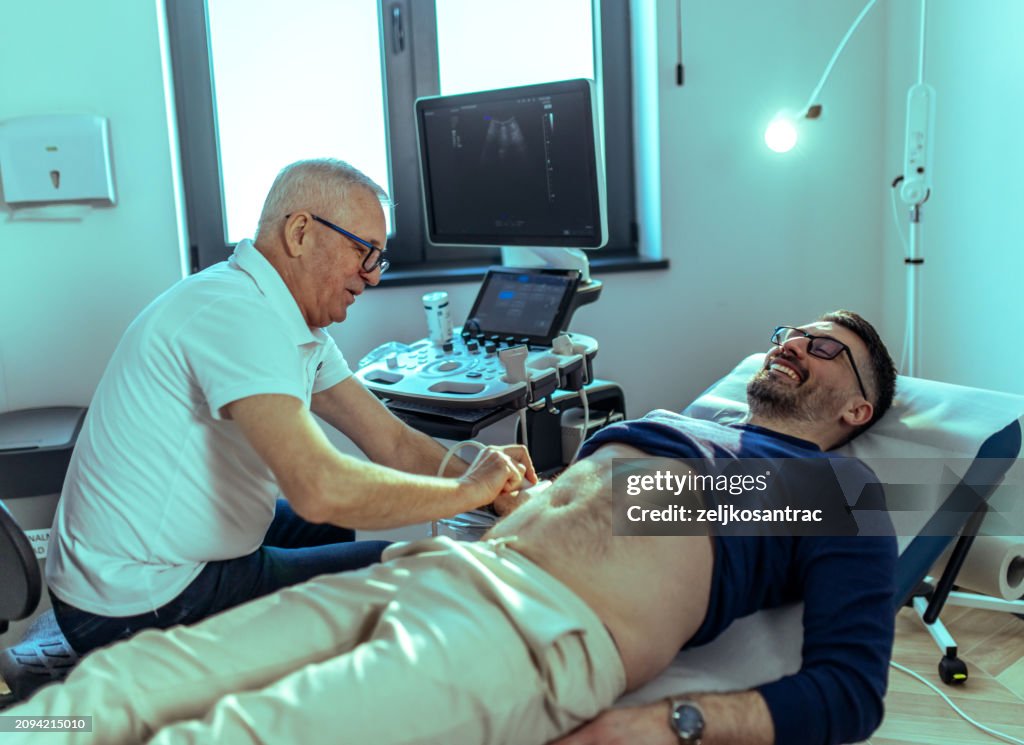A urologist doctor examines a male patient in his office