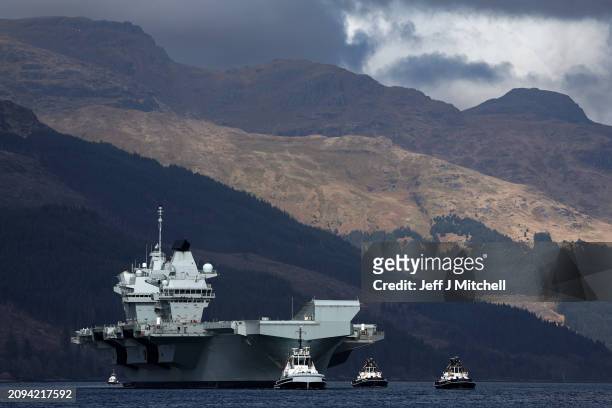 Queen Elizabeth air craft carrier is pulled by tugs on Loch Long on March 18, 2024 in Glenmallan, Scotland. HMS Queen Elizabeth was in Glenmallan in...