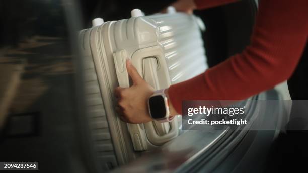 woman loading luggage in car trunk. - achterbak-van-auto stockfoto's en -beelden