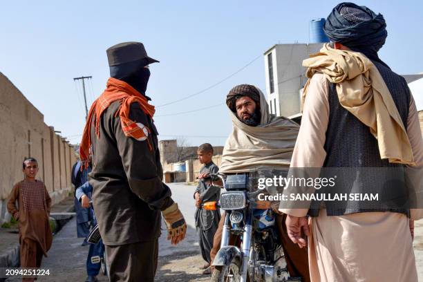 An Afghan security personnel checks a motorbike rider near the site of a suicide bomb attack in Kandahar on March 21, 2024. A suicide bombing killed...