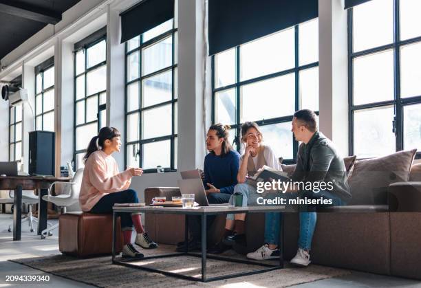 young professionals engaged in brainstorming session at modern co-working space - roupa descontraída imagens e fotografias de stock
