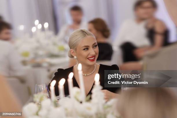 portrait of blonde lady sitting at the table during wedding celebration. - woman wearing pearl necklace stock pictures, royalty-free photos & images