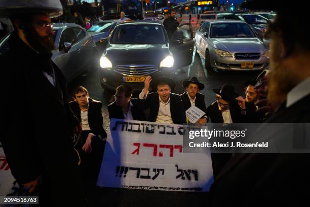 Ultra orthodox Jewish boys and men sit in front of traffic during a protest against the expiration of a law preventing them from being drafted into...