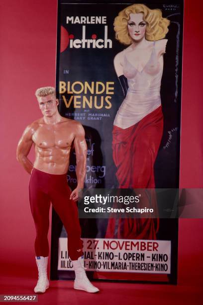 Portrait of Swedish actor Dolph Lundgren as he poses beside a poster for the film 'Blond Venus' , Los Angeles, California, 1985.