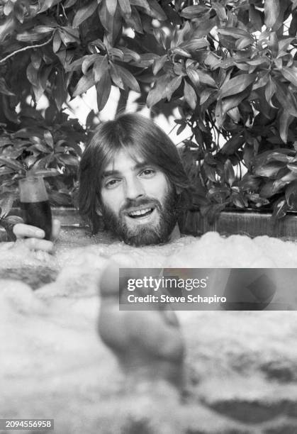 View of American Pop musician Kenny Loggins, a wine glass in his hand, as he sits in a hot tub, Los Angeles, California, 1978.