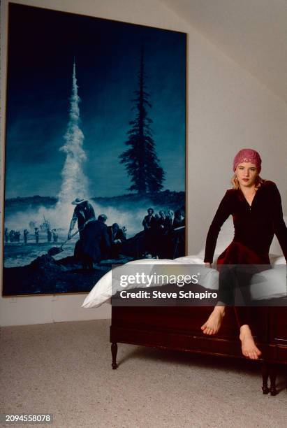 Portrait of American actress Juliette Lewis as she sits on a bed, Los Angeles, California, July 10, 1991. On the wall beside her is a painting by...
