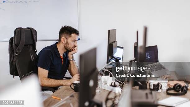 male caucasian developer working on a computer at the office - hand on chin stock pictures, royalty-free photos & images