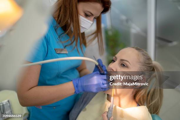 young woman having her teeth checked during appointment at dentist's office. s - plaque remover stock pictures, royalty-free photos & images