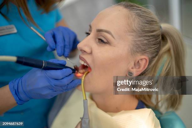 young woman having her teeth checked during appointment at dentist's office. s - plaque remover stock pictures, royalty-free photos & images