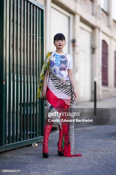 Akimoto Kozue wears a multicolored asymmetric dress, red tights, black pumps, outside Marine Serre, during the Womenswear Fall/Winter 2024/2025 as...