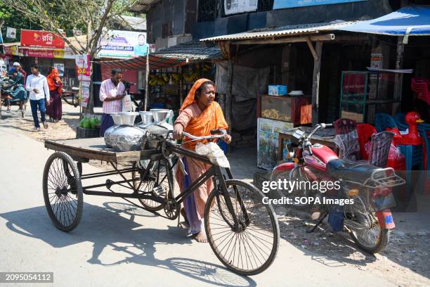 Woman is returning from collecting drinking water on a tricycle from a reverse-osmosis plant set up by a local Non-Governmental Organisation at...