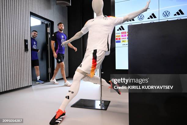 Germany's forward Deniz Undav and Germany's forward Niclas Fuellkrug arrive for a press conference past a mannequin wearing the new German kit made...