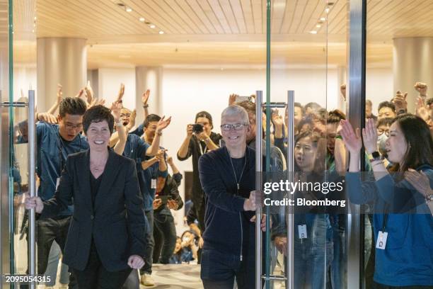 Tim Cook, chief executive officer of Apple Inc., center, and Deirdre O'Brien, senior vice president of retail, left, during the opening of the new...