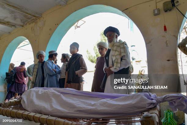 Relatives stand around the dead body of a victim of a suicide bomb attack during a funeral ceremony at a mosque in Kandahar on March 21, 2024. A...