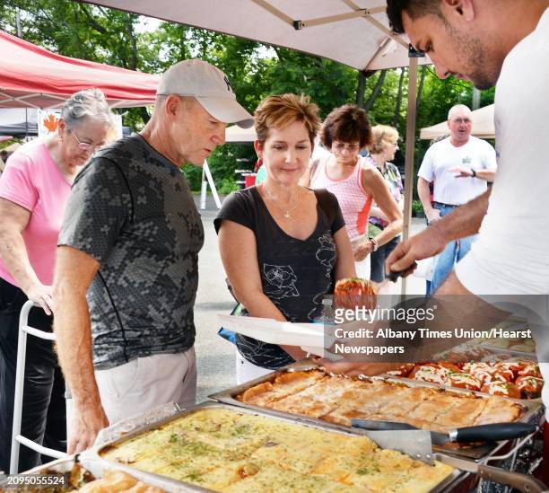 Mike, second from left, and Peggy Conway of Hadley buy European delicacies from Armin Hrelja, right, at the New Covenant Presbyterian Church Farmer's...