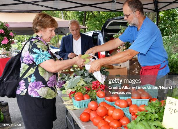 Pat Doyle, left, of Albany buys fresh vegetables from Ken Johnson of Kristy's Barn in Schodack at the New Covenant Presbyterian Church Farmer's...