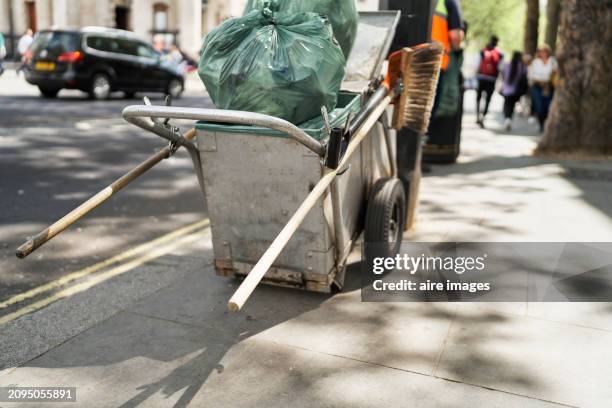 rear view of a cart with garbage bags and broom on the street sidewalk in london - steel railings stock pictures, royalty-free photos & images