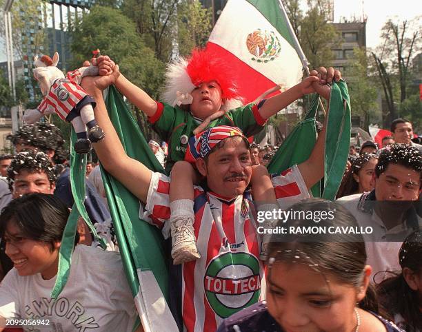 The crowd celebrates their team's victory in Mexico City 11 November 2001. Un hombre levanta en hombros a su pequena hija mientras festeja junto a...