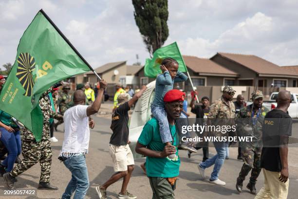 Pan African Congress supporter carries a child on his shoulders who is covering her ears, as they walk with other Pan African Congress supporters on...