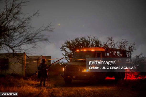 Member of the Mexican Army guards the area in which a charred vehicle and around 10 charred bodies were found, in a section of the Miguel Aleman-Ojo...