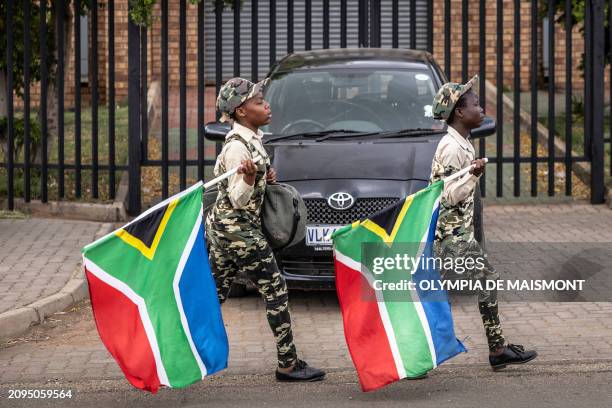 Young men carry South African flags as they walk in the street in Sharpeville on March 21, 2024.