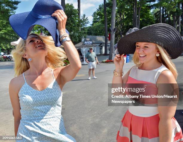 Jill Deitrick, left, of Duryea, Penn., and Stephanie Ward of Kirkwood, NY, learn to handle floppy hats in a breeze on opening day at Saratoga Race...