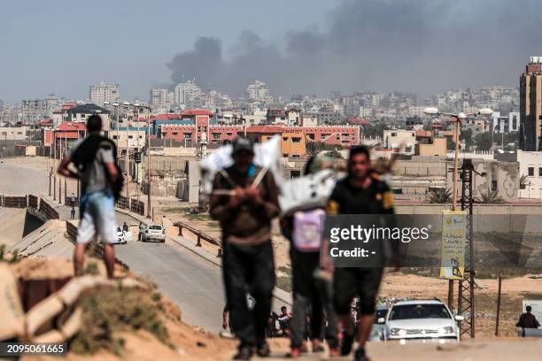 People flee as smoke rises above buildings near the Al-Shifa hospital compound and its vicinity during Israeli bombardment in Gaza City on March 21...
