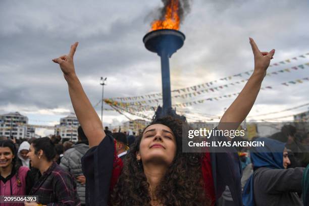 Woman flashes the V-sign in front of a bonfire as Turkish Kurds gather for Nowruz celebrations marking the Persian New Year in Diyarbakir,...