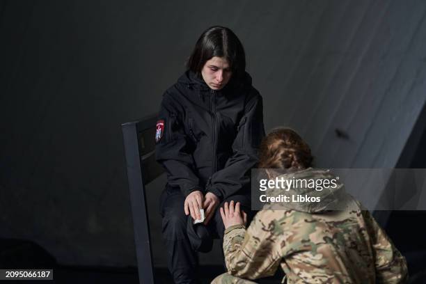 Woman in military uniform comforts another woman as they attend the cremation ceremony of the Combat medic "Troy" in the Kyiv crematorium on March...