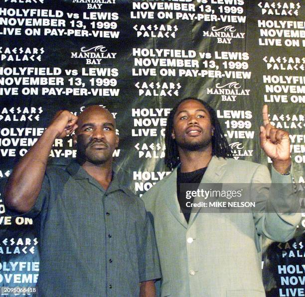 And WBA heavyweight champion Evander Holyfield from the United States poses with WBC heavyweight champion Lennox Lewis from Great Britain following a...