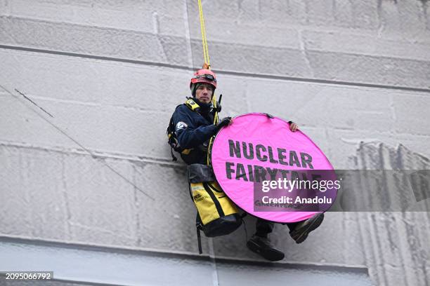 Demonstrators hang from ropes and wave banners from the facade of the venue for the Nuclear Energy Summit in Brussels, Belgium on March 21, 2024....