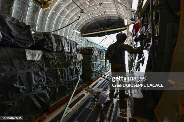 Picture taken on March 21, 2024 onboard a US military transport aircraft shows a US soldier preparing to drop humanitarian aid parcels over the Gaza...