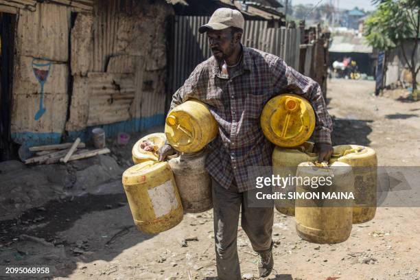 Man carrying empty jerrycans walks towards a water kiosk in Mathare slum in Nairobi on March 21 a day before World Water Day. World Water Day is...