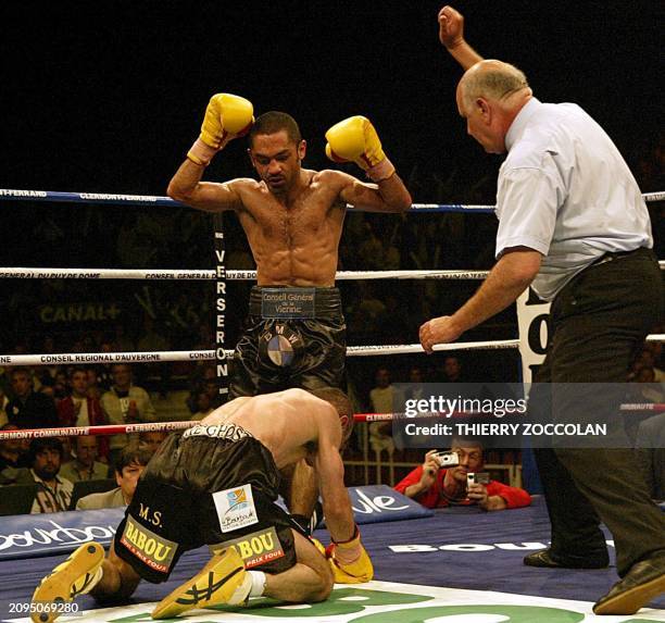 French boxer Mahyar Monshipour raises his arms in victory as compatriot Salim Medjkoune is knocked down, 27 May 2004 in Clermont-Ferrand, during...