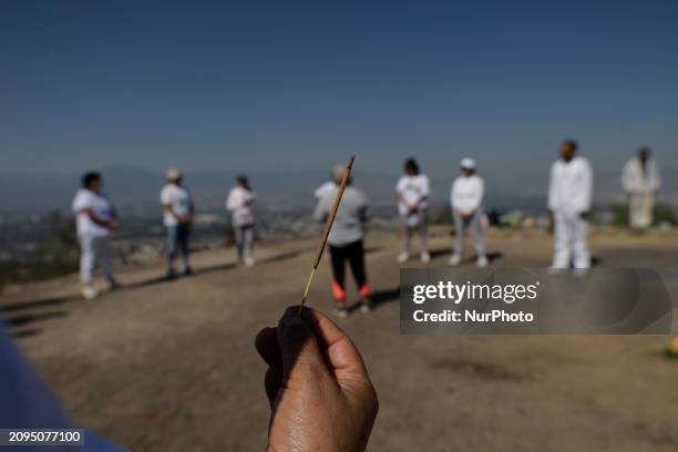 Group of people is visiting the archaeological site of Cerro de la Estrella in Mexico City, where they are performing various rituals, meditating,...