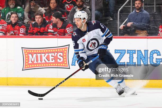 Colin Miller of the Winnipeg Jets skates during the first period of the against the New Jersey Devils at the Prudential Center on March 21, 2024 in...