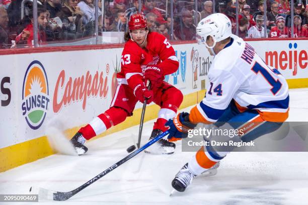 Moritz Seider of the Detroit Red Wings shoots the puck past Bo Horvat of the New York Islanders during the second period at Little Caesars Arena on...