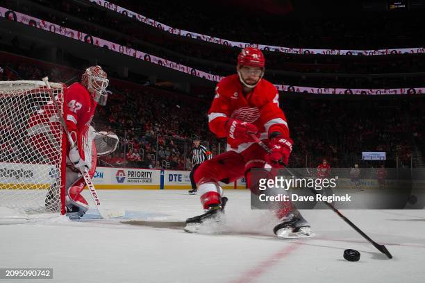 Shayne Gostisbehere of the Detroit Red Wings controls the puck next to James Reimer during the third period of the game against the New York...