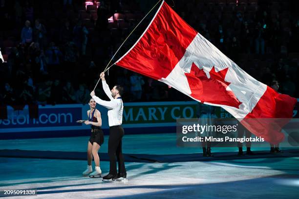 Deanna Stellato-Dudek and Maxime Deschamps of Canada skate with a Canadian flag after finishing first and winning gold in the Pairs Free Program...