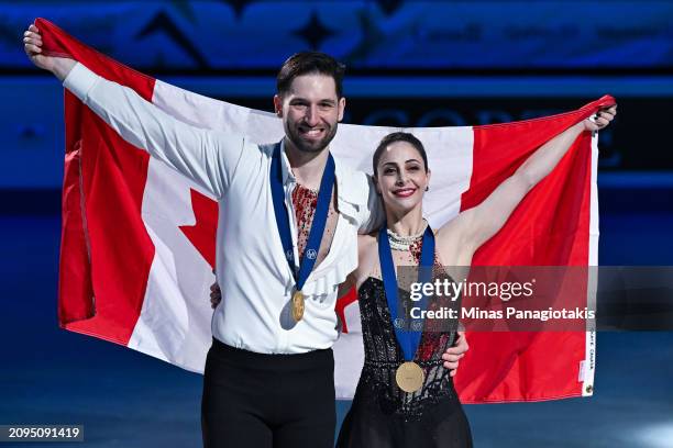 Deanna Stellato-Dudek and Maxime Deschamps of Canada pose with a Canadian flag and their gold medals after finishing first in the Pairs Free Program...