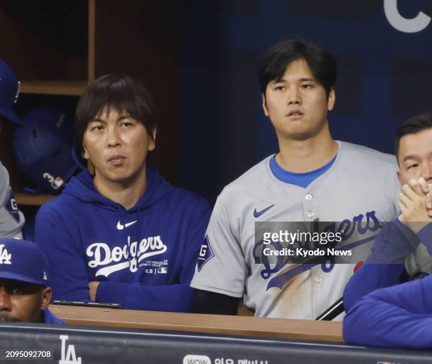 Shohei Ohtani of the Los Angeles Dodgers and his interpreter Ippei Mizuhara watch Major League Baseball's season-opening game against the San Diego...