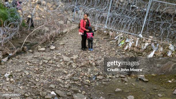 In an aerial view, immigrants are blocked by razor wire after crossing the Rio Grande into the United States on March 18, 2024 in Eagle Pass, Texas....