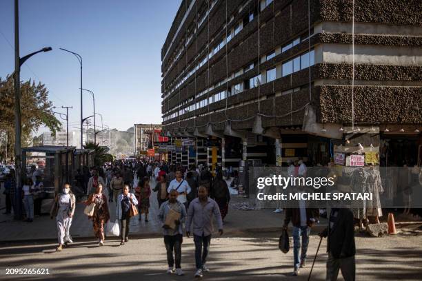 People walk past business and shops in the 4 Kilo neighbourhood of Addis Ababa on March 21, 2024. The city of Addis Ababa has undertaken a new urban...
