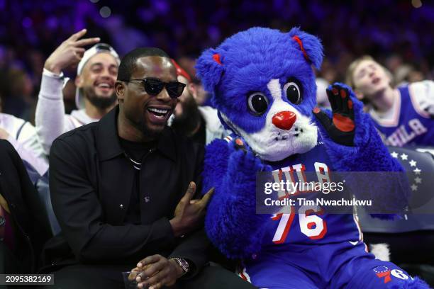 Fitness personality Alex Toussaint poses for photos with Philadelphia 76ers mascot, Franklin, during the fourth quarter between the Philadelphia...